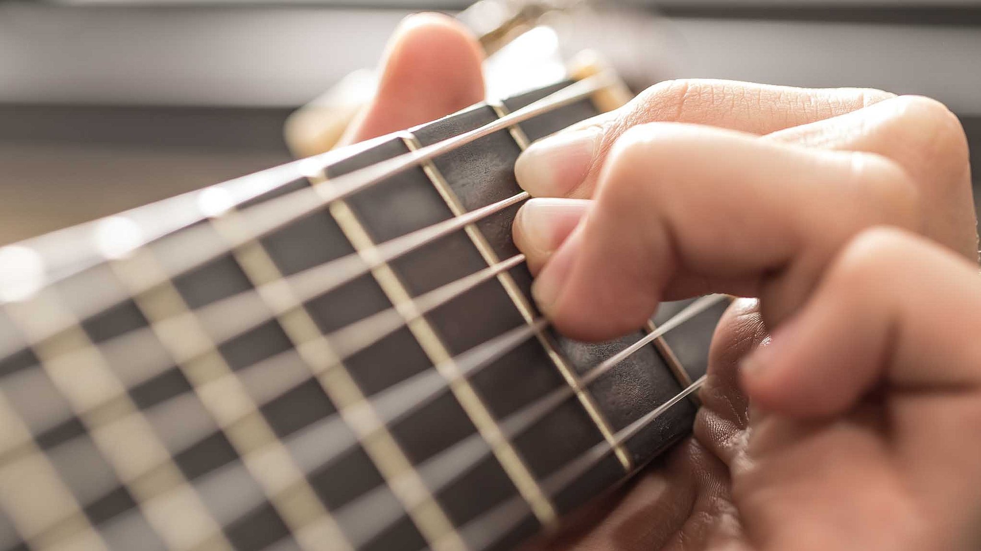 Greifhand am Griffbrett einer Gitarre