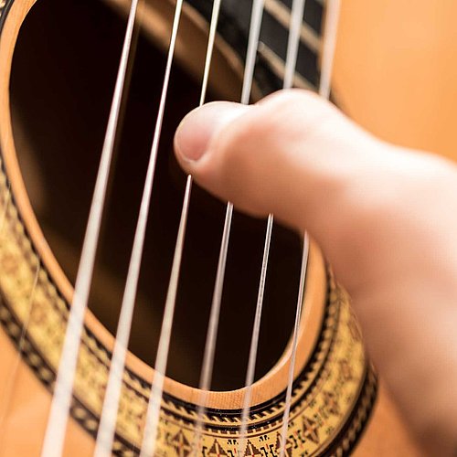 Spielhand am Schallloch einer Gitarre